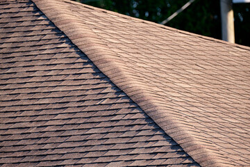 Closeup of house roof top covered with asphalt or bitumen shingles. Waterproofing of new building
