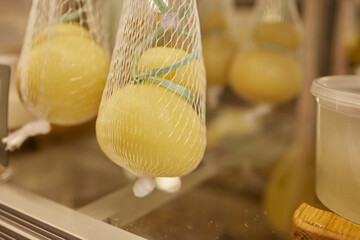 Delicious fresh Caciocavallo and Scamorza cheese hanging. Italian cheeses close up. The cheeses are...