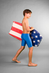 Boy in blue swim suit walking with a boogie board under his arm