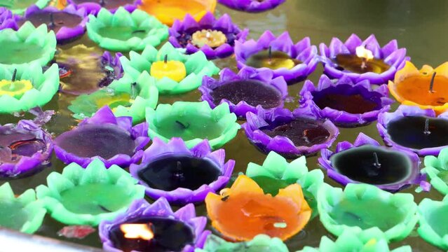 Decorative candles float on water in a tank in a Buddhist temple, Thailand