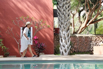 Latin adult woman walks next to a pool, she feels relaxed, fulfilled, calm, calm and well-being, she sunbathes in freedom and peace