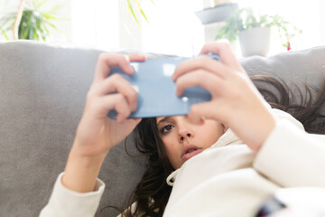 Teenage girl watching her mobile phone at home on the sofa
