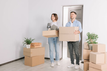 Happy couple with moving boxes entering in new apartment