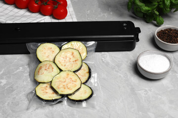 Sealer for vacuum packing and plastic bag with cut eggplant on light grey marble table