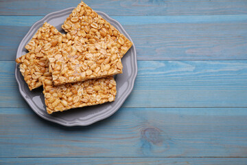 Delicious peanut bars (kozinaki) on light blue wooden table, top view. Space for text