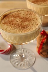 Tasty eggnog with cinnamon on white table, closeup