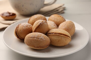 Homemade walnut shaped cookies with condensed milk on white table, closeup