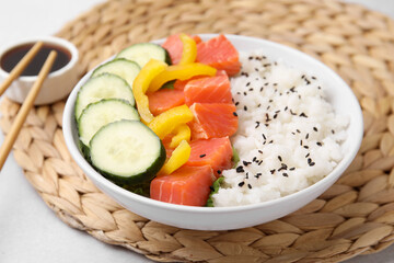 Delicious poke bowl with salmon, rice and vegetables on white table, closeup