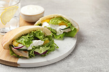 Delicious pita sandwiches with chicken breast and vegetables on light gray table, closeup