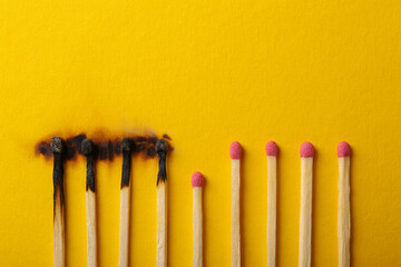 Burnt and whole matches on yellow background, flat lay. Stop destruction by breaking chain reaction concept - obrazy, fototapety, plakaty