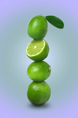 Stacked whole and cut limes on violet blue background