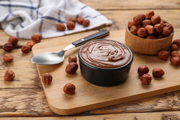 Bowl with delicious chocolate paste and nuts on wooden table