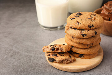 Stack of delicious chocolate chip cookies and milk on grey table. Space for text