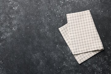 Beige checkered tablecloth on black textured table, top view. Space for text