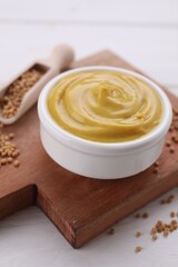 Bowl with delicious mustard and seeds on white wooden table