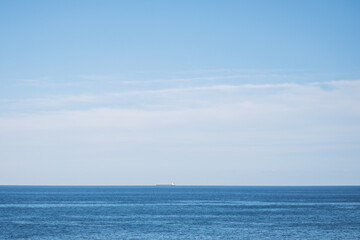 Obraz premium 広い空と大きな海、遠くに小さく見える貨物船
