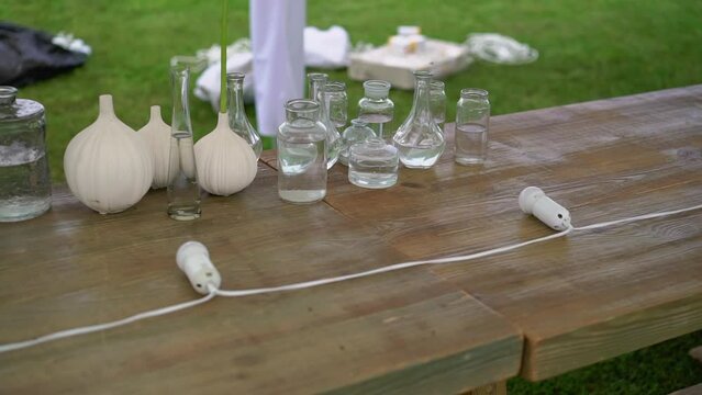 Glass transparent flower vases with water on the table. Preparation for holiday, party, wedding reception.