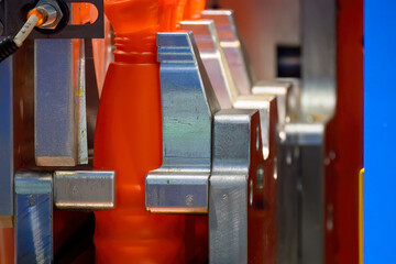 Close up scene the orange plastic bottle container manufacturing process by blow mold machine.