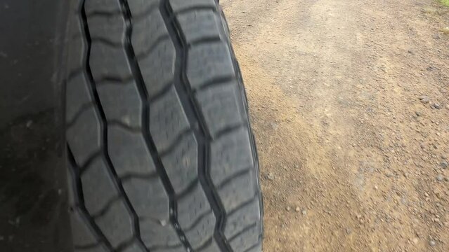 Off-road vehicle wide tire tread closeup driving dirt road turning rocky terrain