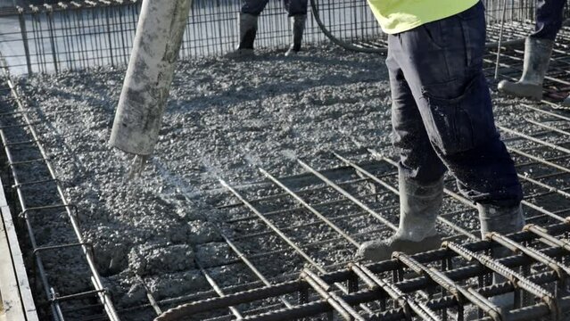 workers apply a layer of cement to create the floor and roof of a large area under construction