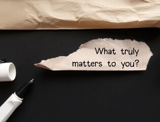 Torn envelope on black background with handwritten text - What truly matters to you? question of self awareness, to consider what priorities are and focus on what matters most - obrazy, fototapety, plakaty
