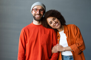 Happy stylish romantic couple embracing, looking at camera standing together at new home. Portrait of smiling attractive confident best friends wearing colorful clothing. Love, relationship concept 