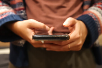 Closeup scrolling phone. Defocus female hand holding black phone. Close up of a woman using mobile smartphone. Millennial style. Social media. Out of focus