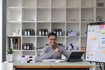 Fototapeta na wymiar millennial office employee in glasses sitting at desk in front of laptop smiling looking at camera. Successful worker, career advance and opportunity, owner of prosperous business concept