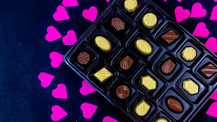 delicious chocolate surrounded by pink hearts on black background