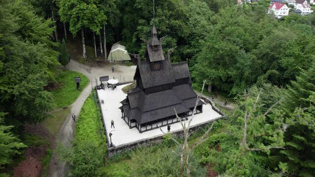 Aerial view away from the Stave church in cloudy Fantoft, Norway - reverse, tilt, drone shot