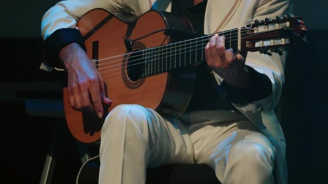 Flamenco guitarist in white suit plays flamenco music chords