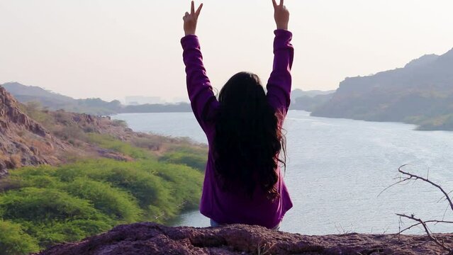 isolated young girl at mountain top with lake view backbit shot from flat angle video is taken at kaylana lake jodhpur rajasthan india.