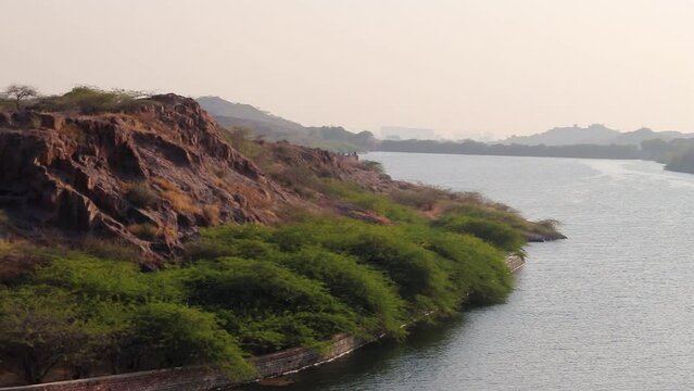 isolated young girl at mountain top with lake view backbit shot from flat angle video is taken at kaylana lake jodhpur rajasthan india.
