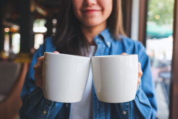 Fototapeta Closeup image of a young woman holding and serving two cups of hot coffee obraz