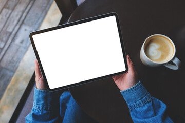 Top view mockup image of a woman holding digital tablet with blank white desktop screen in cafe