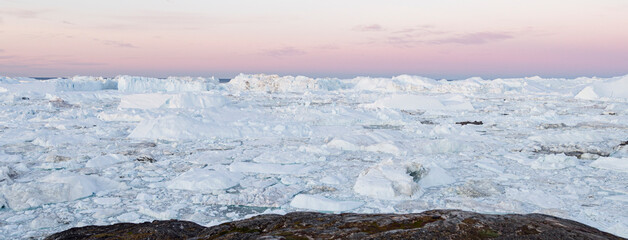Global Warming and Climate Change. Iceberg from melting glacier in Ilulissat, Greenland. Midnight sun in arctic nature landscape famous as heavily affected by global warming. Panoramic banner © Maridav