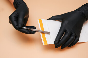 The hands of the manicure master remove the manicure and pedicure tools in a sterilization bag on a...