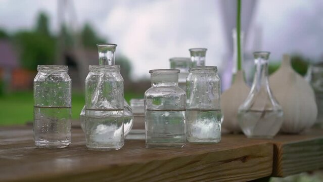 Glass transparent flower vases with water on the table. Preparation for holiday, party, wedding reception.