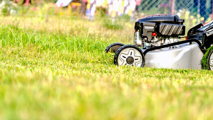 Fototapeta na wymiar Lawn mover on green grass in modern garden. Machine for cutting lawns.