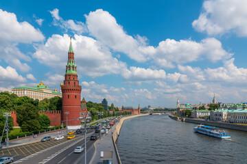 Fototapeta premium View of Kremlin with Vodovzvodnaya tower, Grand Kremlin Palace from repaired Bolshoy Kamenny Bridge in Moscow city on sunny summer day. Cruise ship sails on the Moscow river