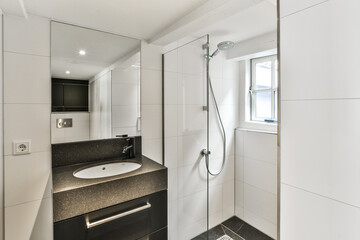 a modern bathroom with black and white tiles on the walls, sink, mirror, and shower stall in it