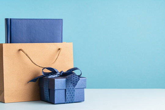 small Luxury gift box with a blue bow paper bag and agenda. Side view. Fathers day or Valentines day gift for him. Corporate gift concept or birthday party. Festive sale copy space