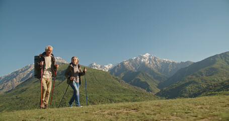 Obraz premium Mature caucasian couple on vacation, having a hike in spring mountains, spending time together after retirement together travelling - tourism, pension concept