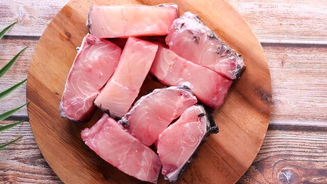 Fresh boneless skinless cod filet on chopping board 