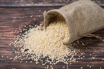 white sesame seeds in sack on wooden table