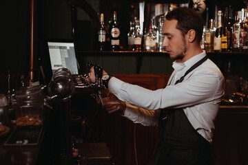bartender at the bar pours beer into a glass with a tap from a keg