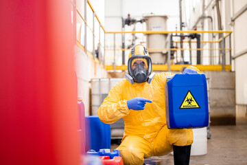 Recycling plant worker in protection suit and gas mask disposing biohazard and toxic material.