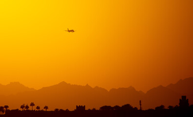 Silhouette of an airplane coming in for landing at sunset.