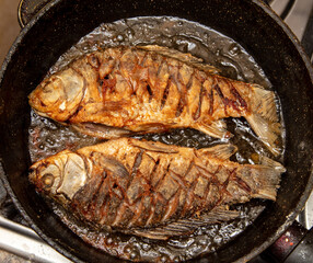 The fish is fried in oil in a frying pan.