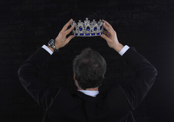 businessman wears a crown, black background